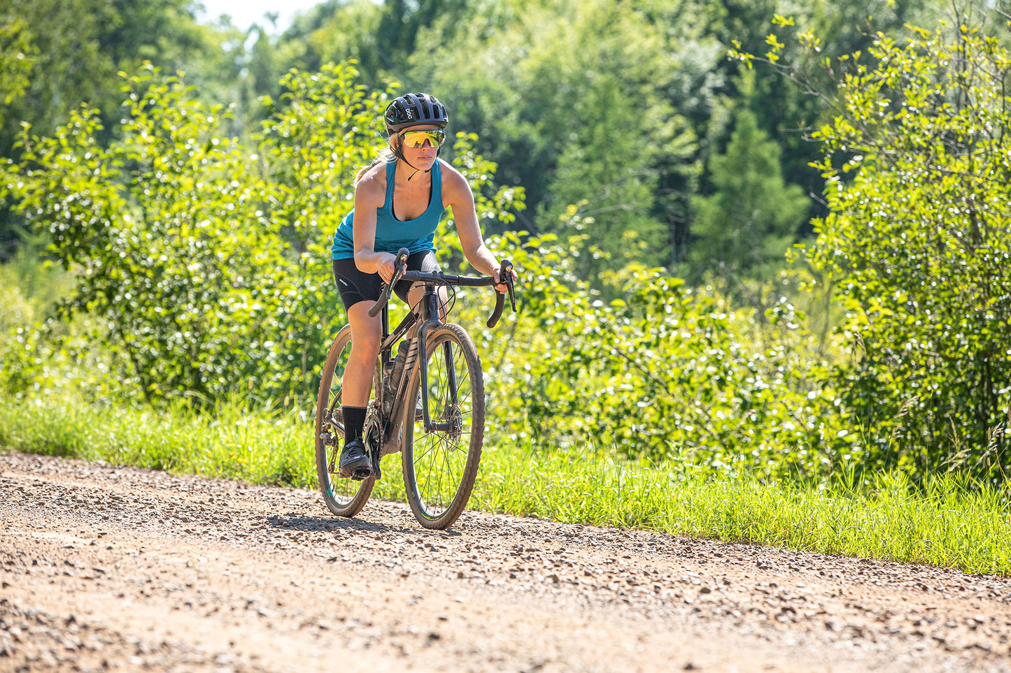 Woman riding a bicycle on a dirt path in a forested area