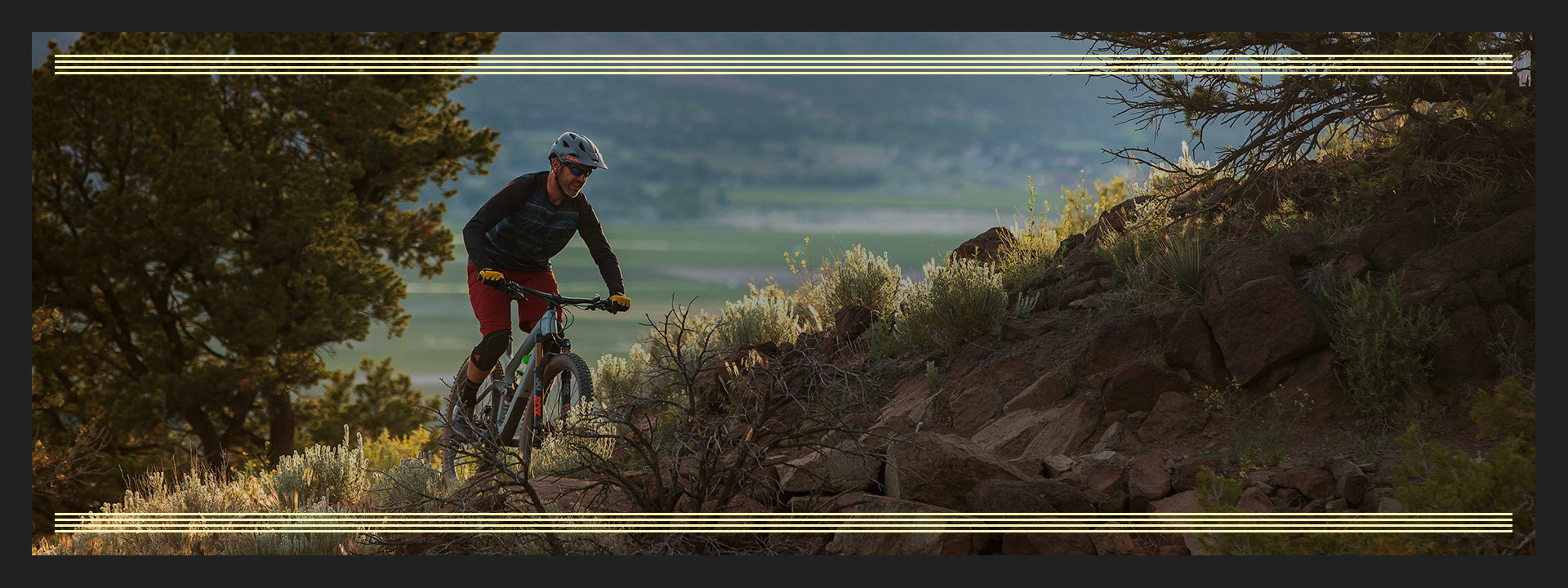 Person mountain biking on a trail with a scenic background