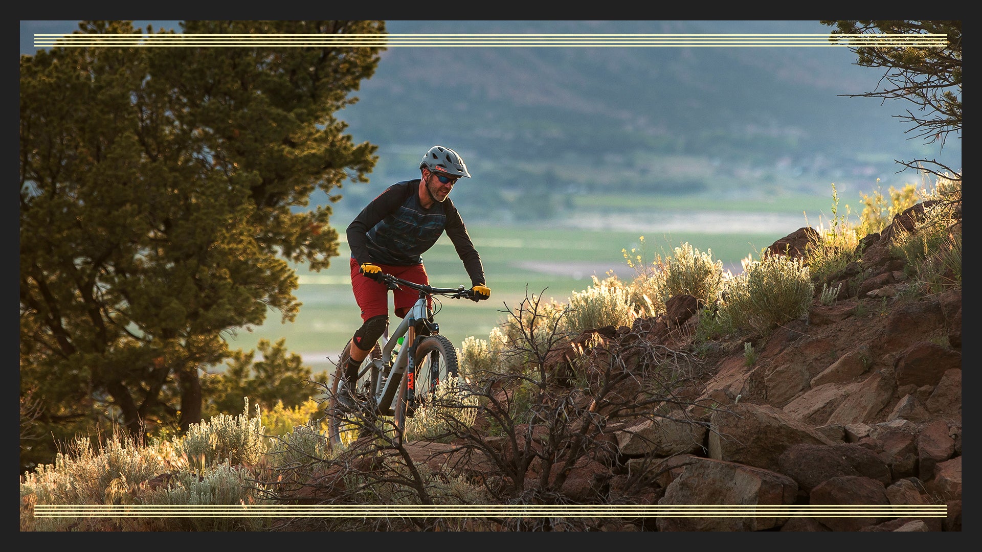 Person mountain biking on a trail with scenic landscape