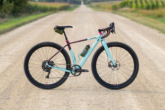 Light blue bicycle on a dirt road with greenery in the background