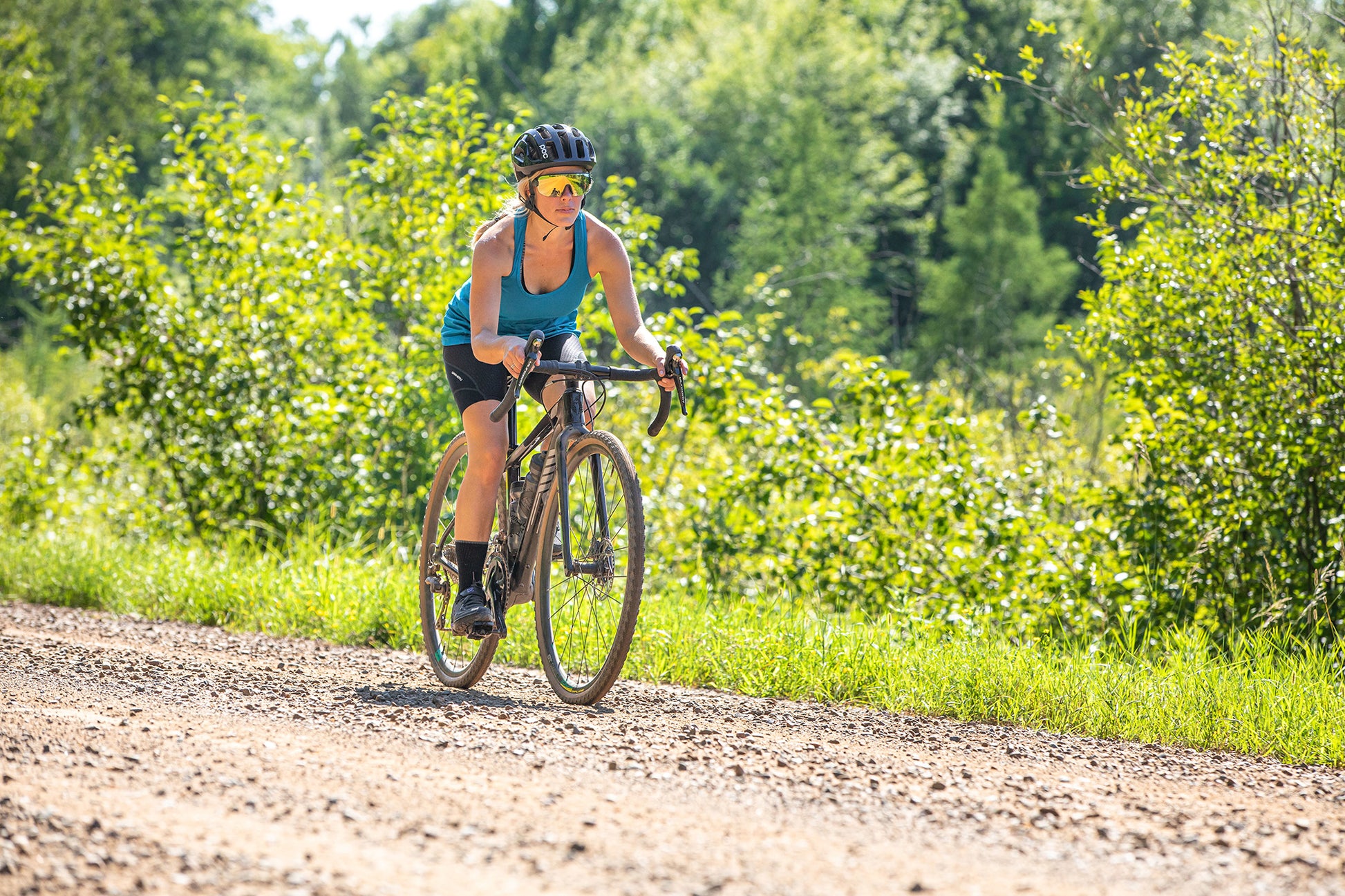 Woman riding a bicycle on a dirt path in a forested area