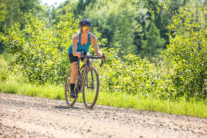 Woman riding a bicycle on a dirt path in a forested area