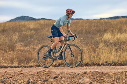Person cycling on a dirt road with a scenic background
