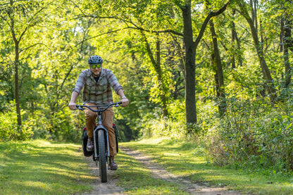 Person riding a bicycle on a trail through a forest