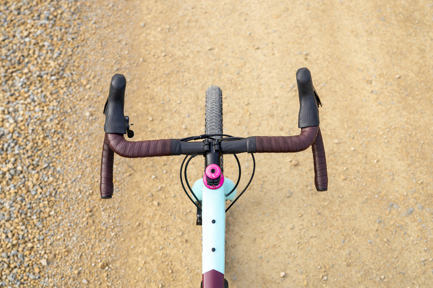 Close-up of a bicycle handlebar with a gravel road in the background