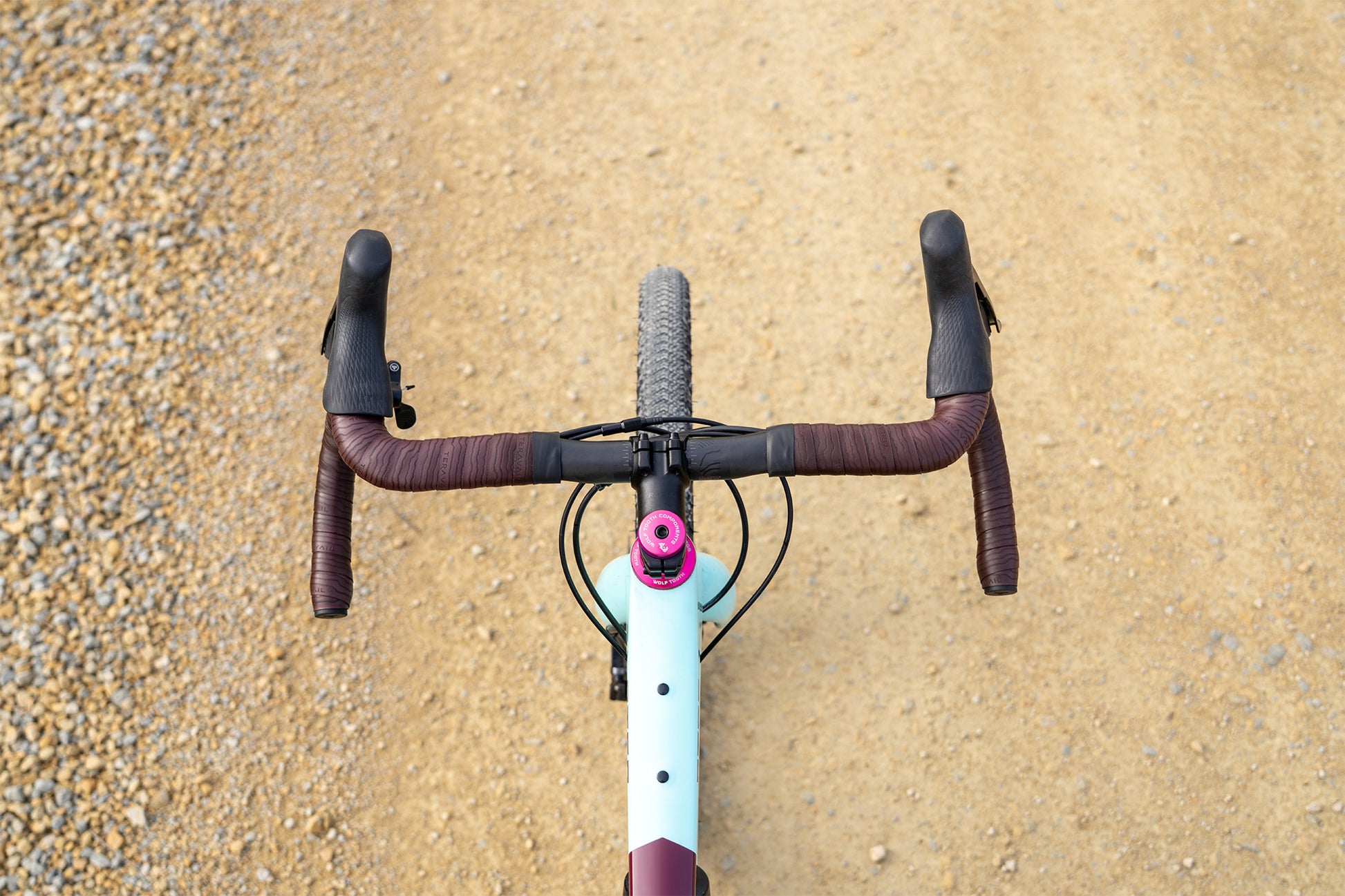 Close-up of a bicycle handlebar with a gravel road in the background