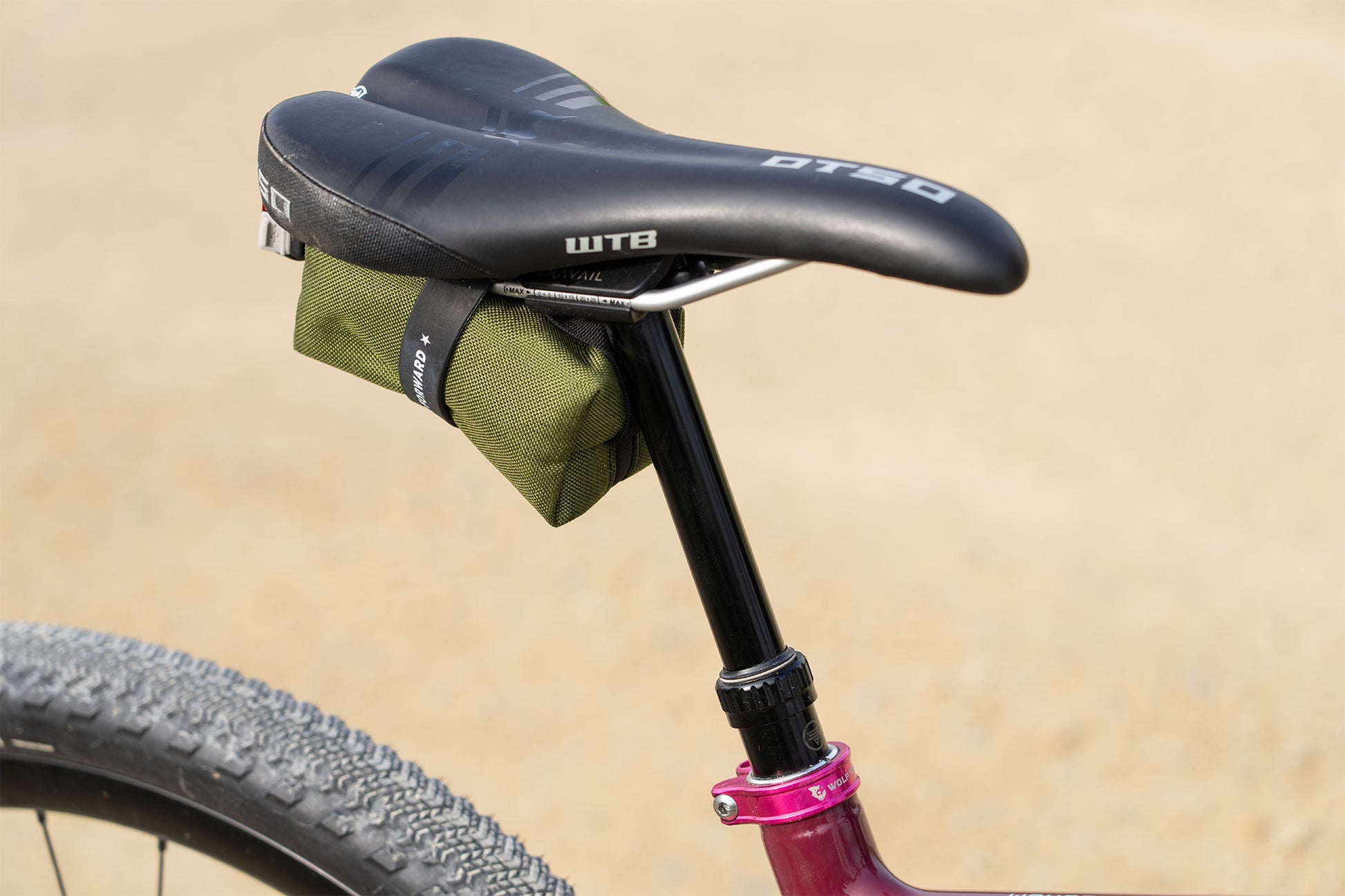 Bicycle seat with a green bag attached on a beige background