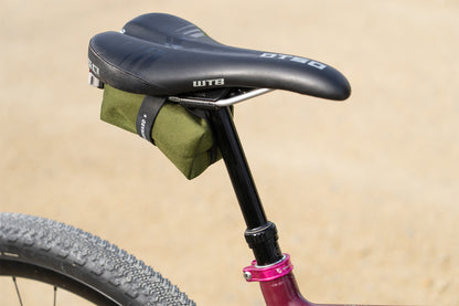 Bicycle seat with a green bag attached on a beige background
