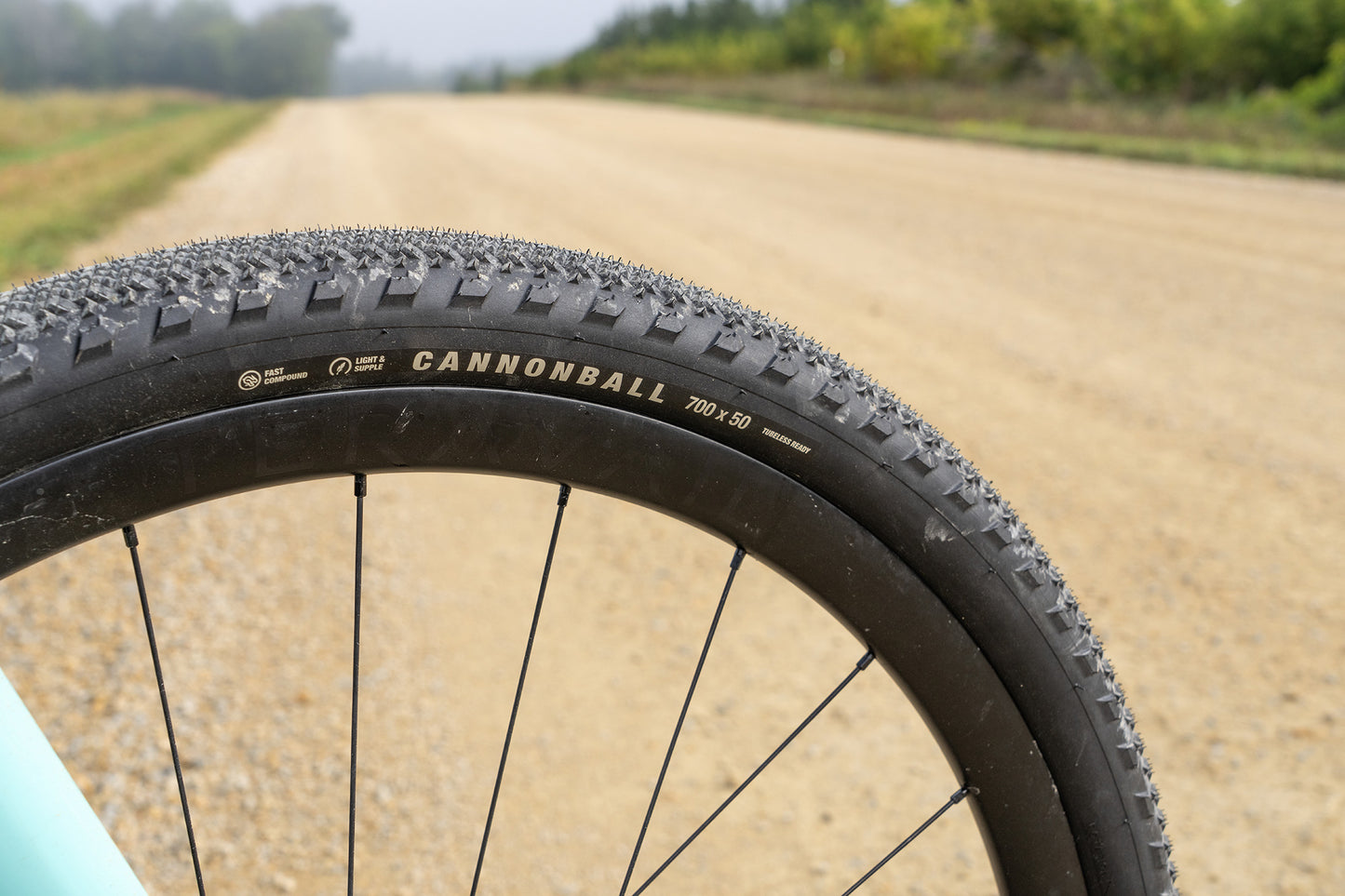 Close-up of a bicycle tire with 'Cannonball' branding on a dirt road.