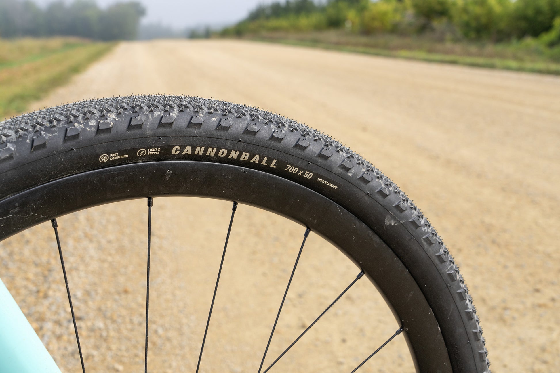 Close-up of a bicycle tire with 'Cannonball' branding on a dirt road.