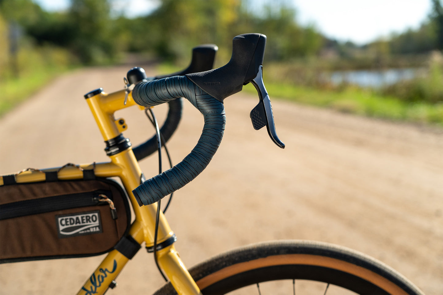 Yellow bicycle with handlebars and a bag on a blurred natural background