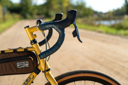 Yellow bicycle with handlebars and a bag on a blurred natural background