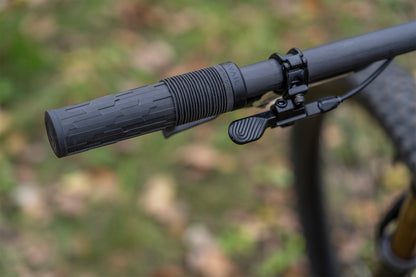 Close-up of a bicycle handlebar with grip and brake lever against a blurred natural background