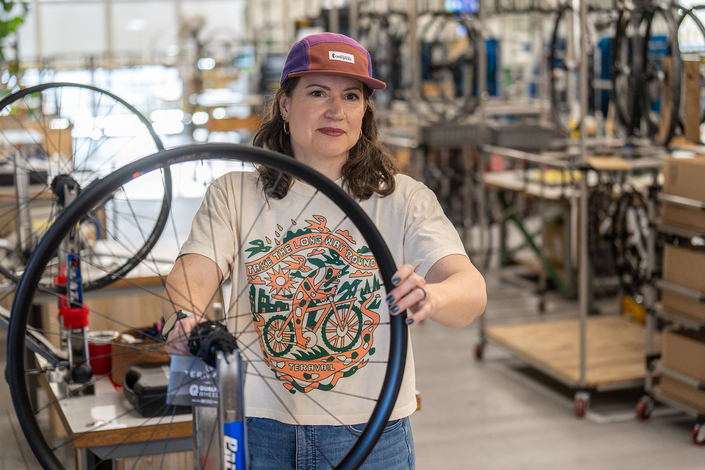 Person holding a bicycle wheel in a workshop setting