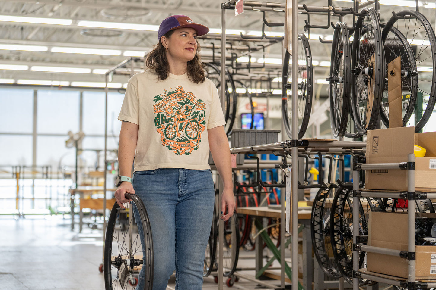 Person in a factory setting with bicycle wheels and parts around