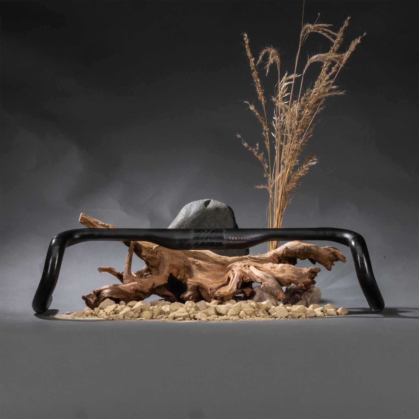 Decorative setup with black carbon drop bar, driftwood, stones, and dried plants on a dark background