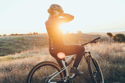 Person on a bicycle in a field with sunset light