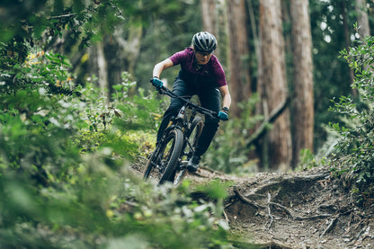 Person riding a mountain bike through a forest trail