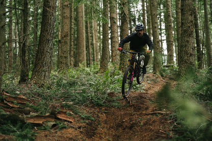 Person riding mountain bike in dense forest trail