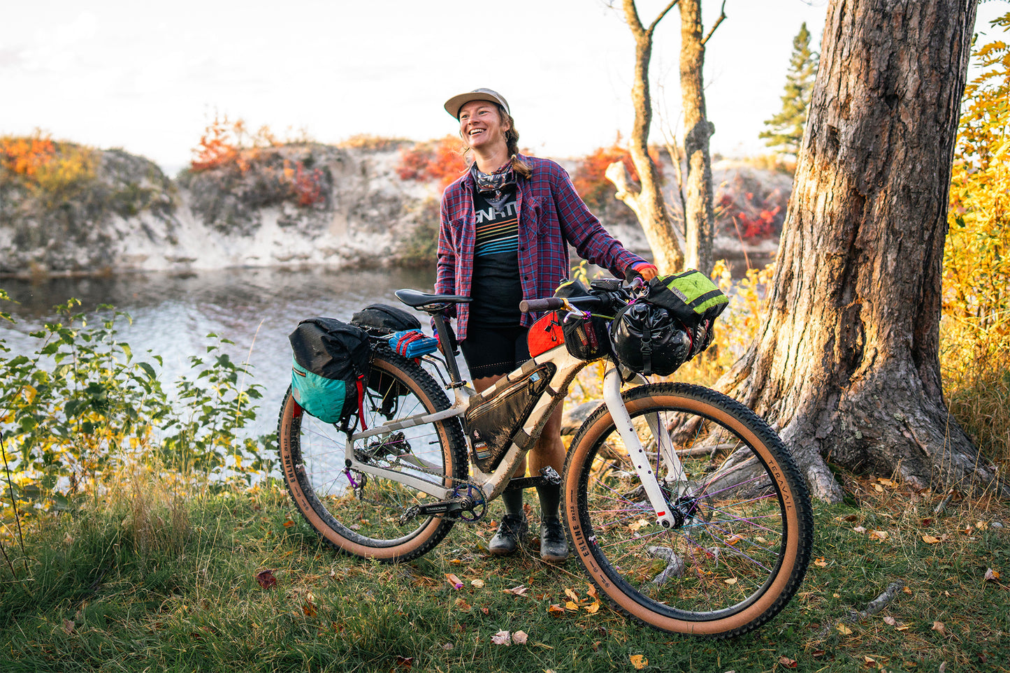 Person with a bicycle loaded with gear by a lake in autumn
