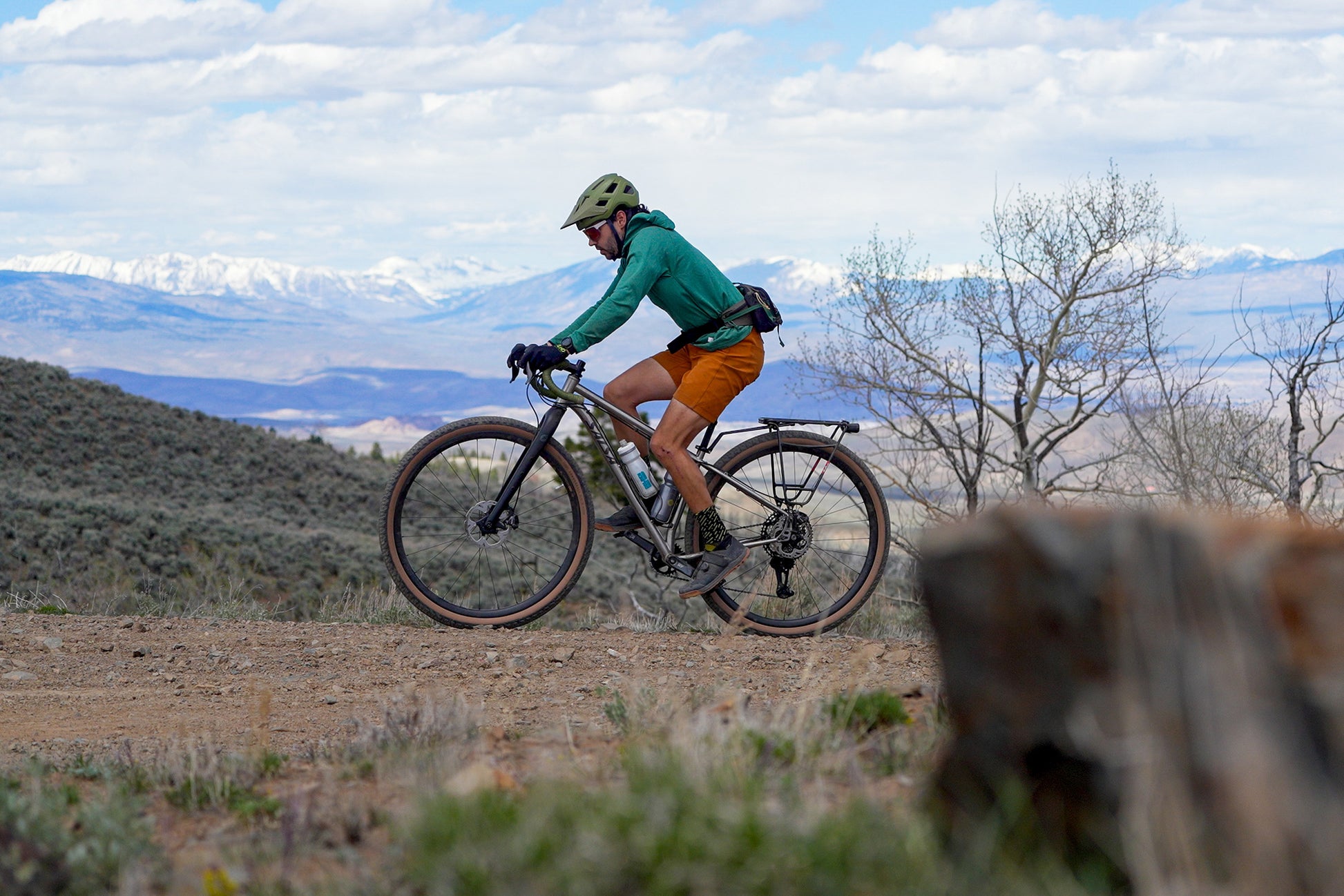 Cyclist riding Salsa Fargo 32 bike with Teravail Cannonball 32 tires on gravel road with mountains in background