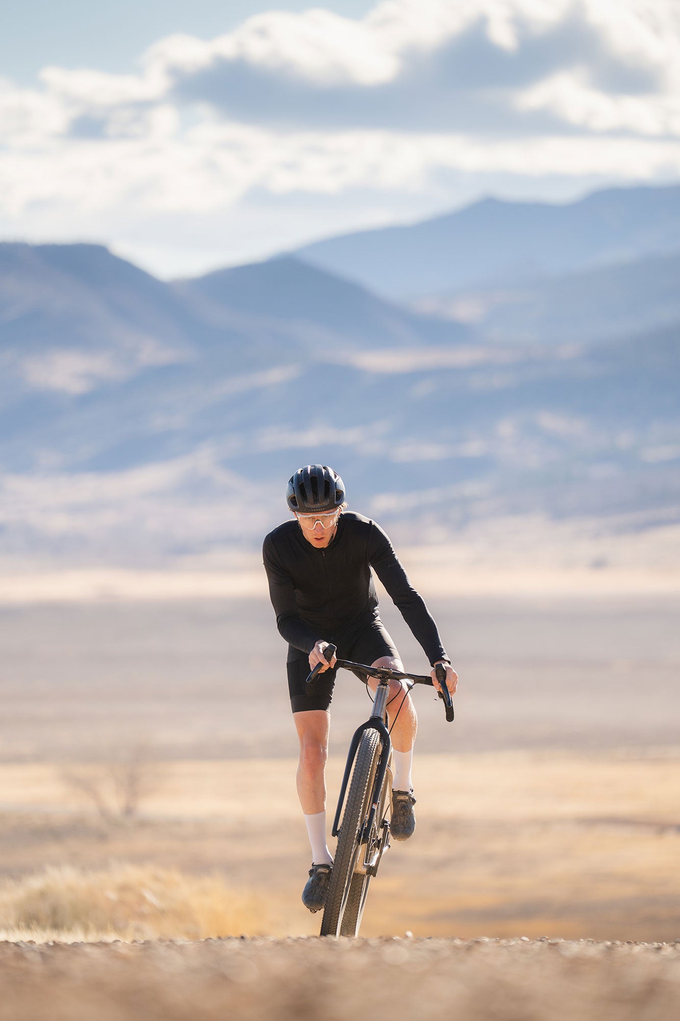 Person cycling on a dirt road with mountains in the background