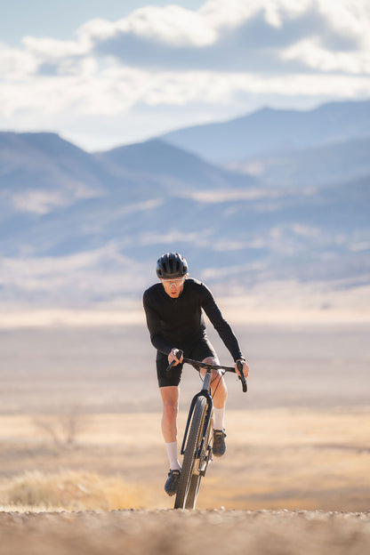 Person cycling on a dirt road with mountains in the background