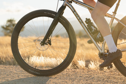 Close-up of a cyclist on gravel with front wheel focus on a gravel road with a blurred natural background