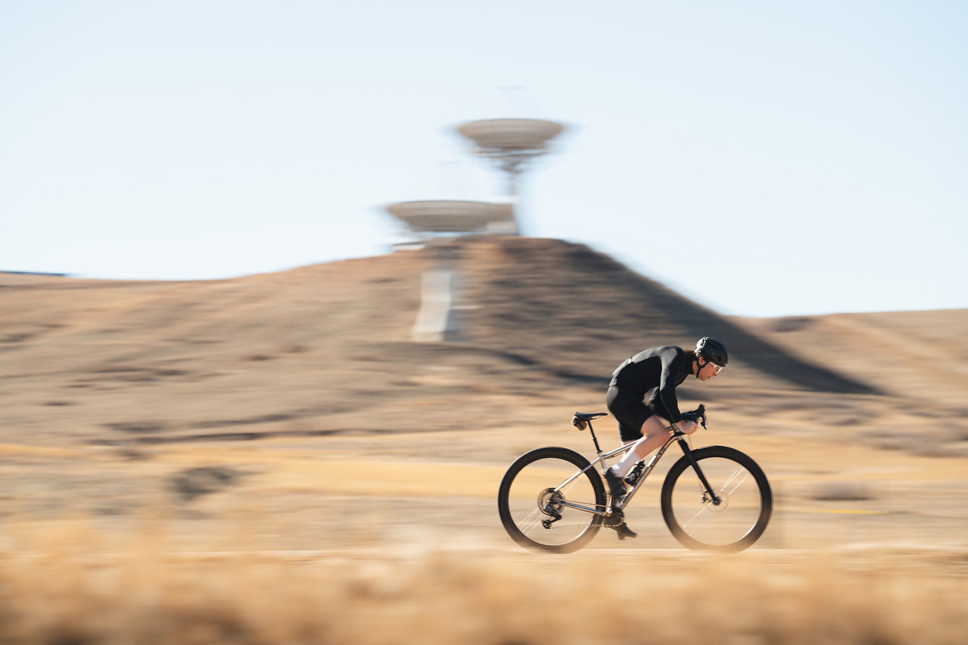 Person riding a bicycle on a desert landscape with a clear sky.