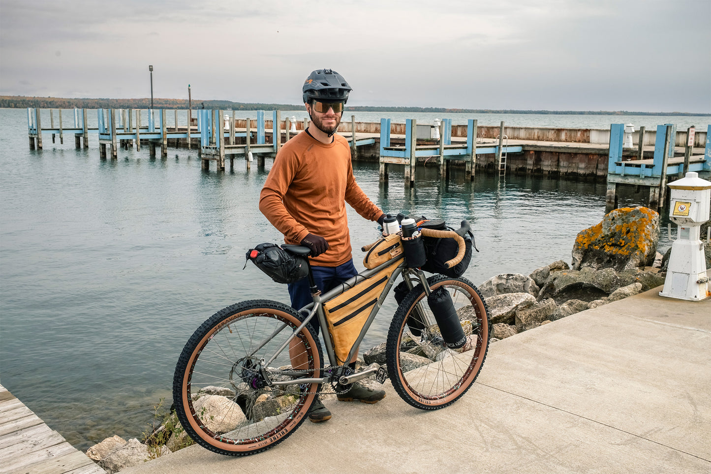 Person with a bicycle by a waterfront with a pier in the background