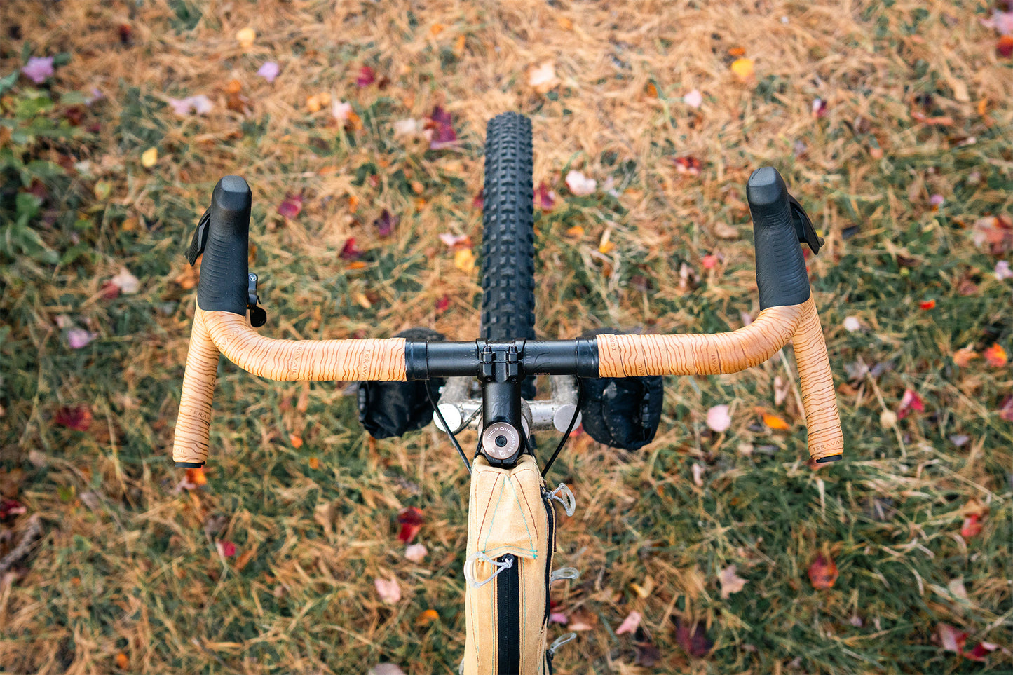 Bicycle handlebar with tan bar tape on a grassy background