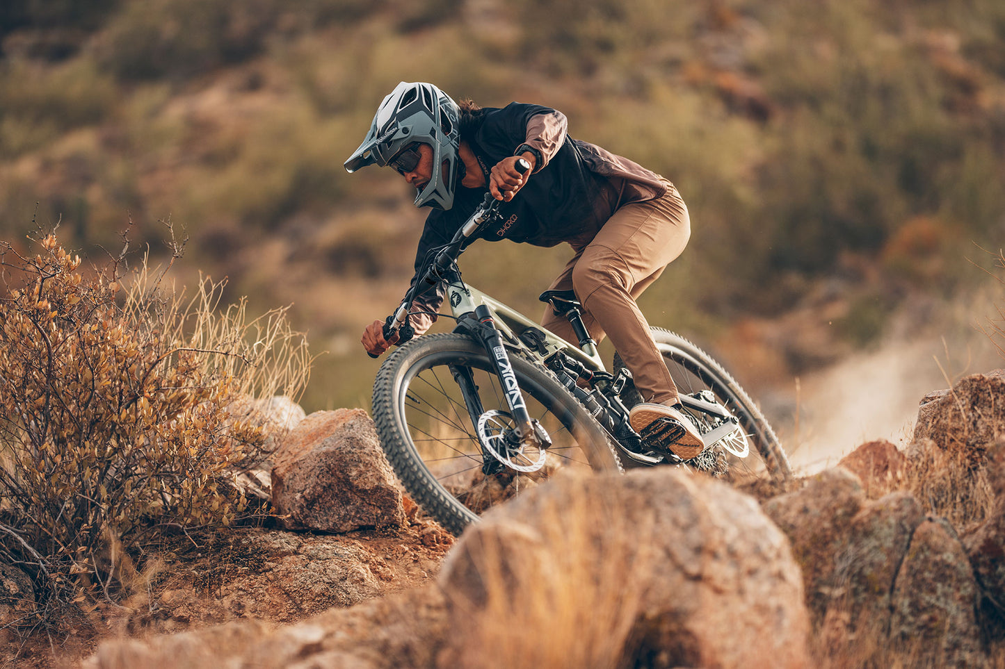 Person riding a mountain bike on rocky terrain with a blurred natural background