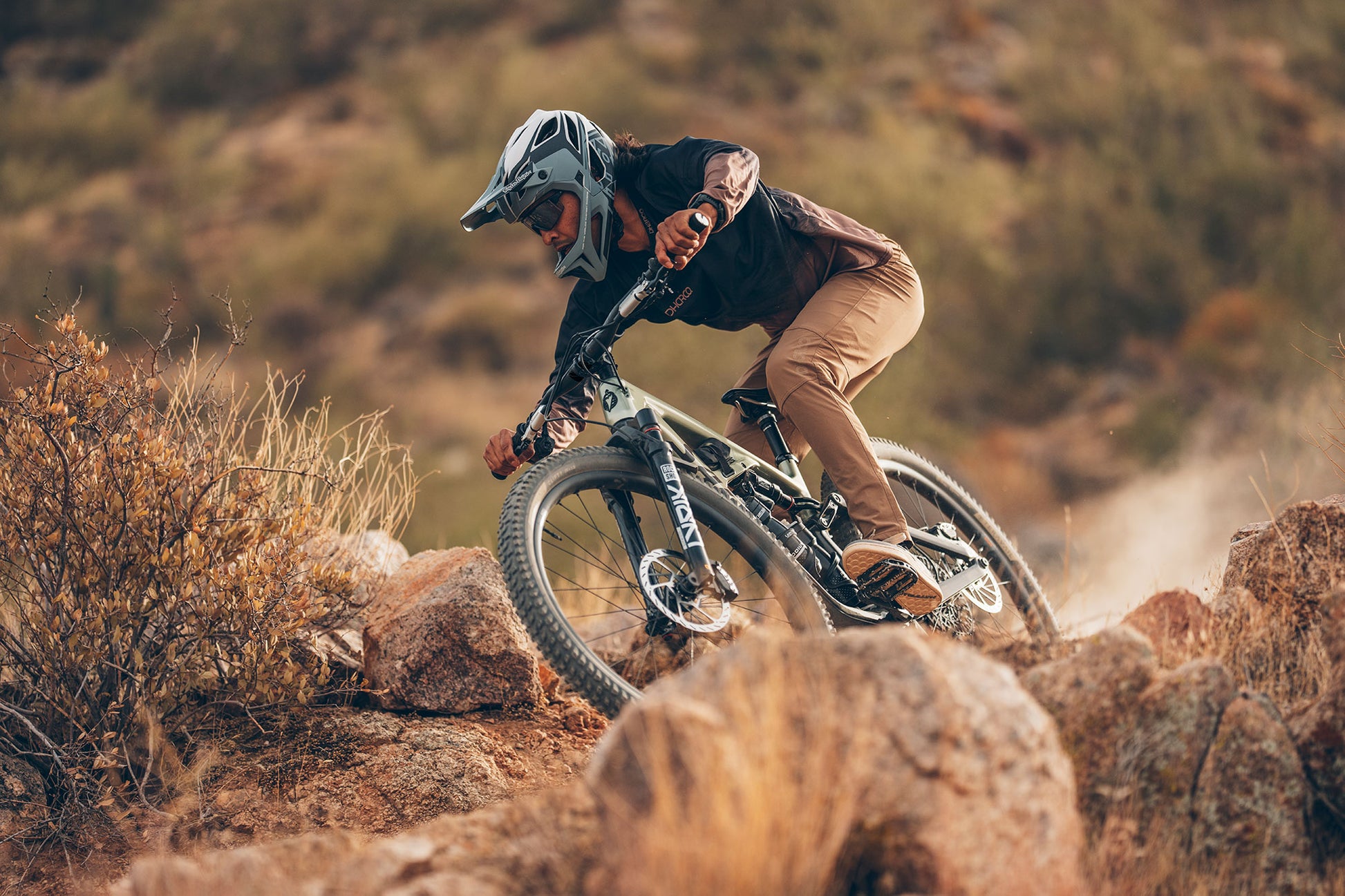 Person riding a mountain bike on rocky terrain with a blurred natural background