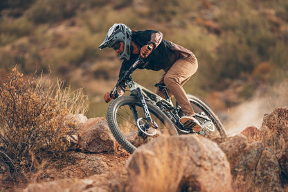 Person riding a mountain bike on rocky terrain with a blurred natural background