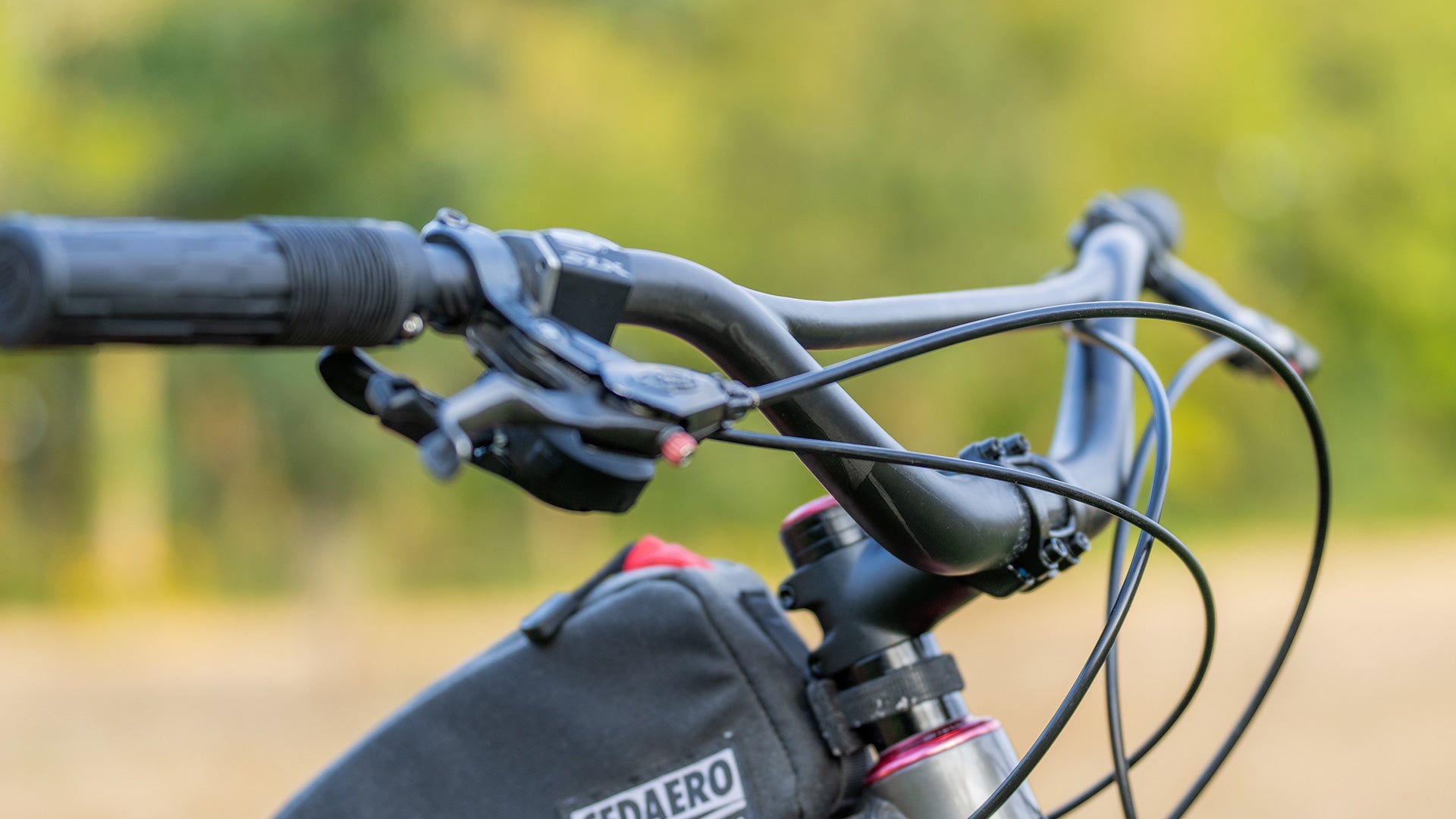 Close-up of bicycle handlebars with blurred greenery in the background
