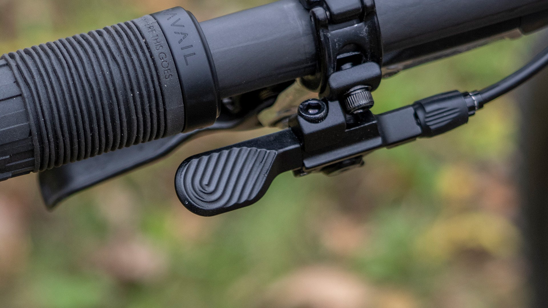 Close-up of dropper remote lever on bike handlebar with blurred natural background