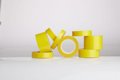 Yellow tape rolls stacked on a white surface with a light gray background